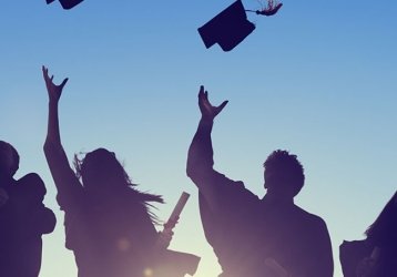 Silhouette of individuals in graduation robes throwing their hats