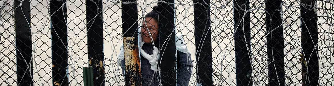 image of an individual behind a barbwire fence