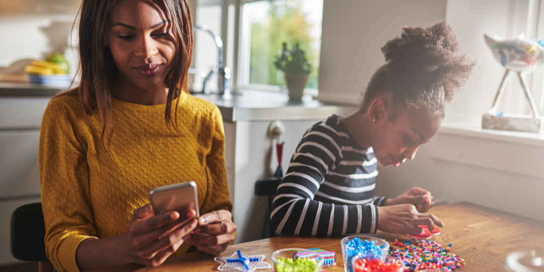 A women looking at a phone next to her child